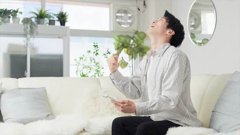 スマホを持ってガッツポーズをする様子
